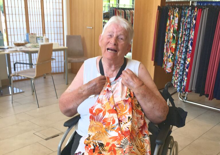 Bewohnerin hält Kleid in der Hand und freut sich darüber.