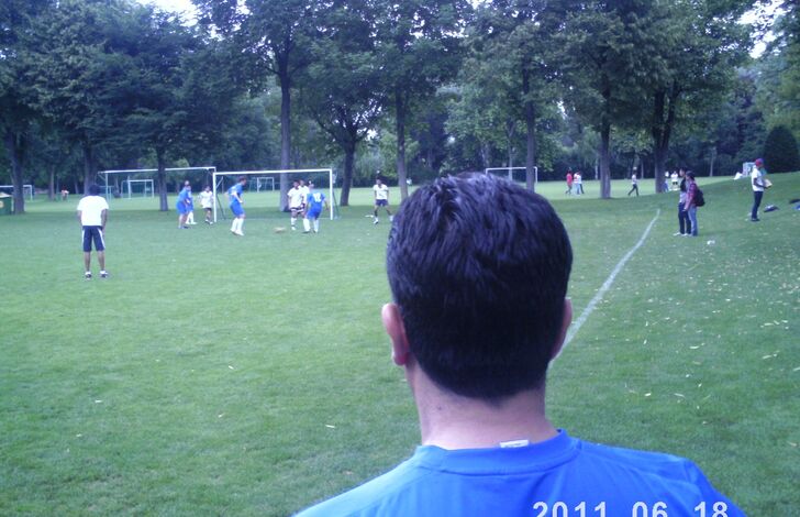 Birkent von hinten, wie er auf das Fußballfeld blickt. Es ist gerade ein Spiel im Gange. (outdoor)