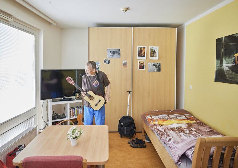 Kunde spielt in seinem individuell eingerichteten Zimmer in der HABIT WG Attemsgasse auf der Gitarre