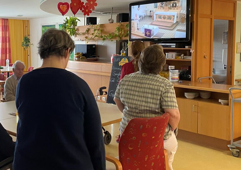 Bewohnerinnen und Mitarbeiterinnen verfolgen die TV-Übertragung.