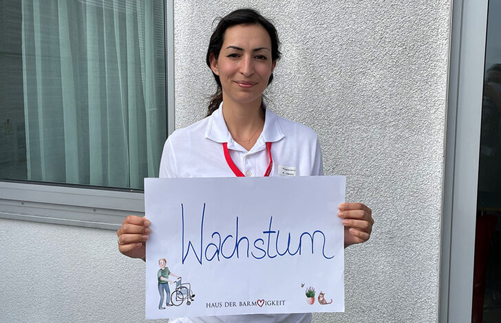 Mitarbeiterin hält Schild mit "Wachstum"