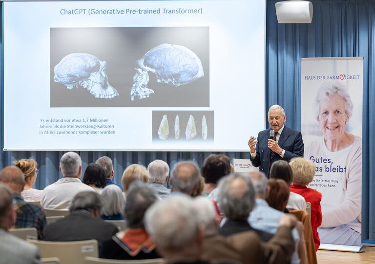 Johannes Huber präsentiert Vortrag - Publikum sieht zu