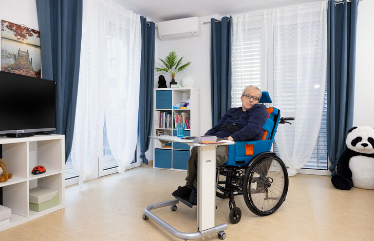 Kunde im Rollstuhl im Wohnzimmer.