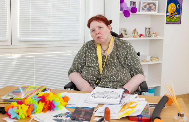 Nahaufnahme Kundin, sie blickt in die Kamera und sitzt am Basteltisch