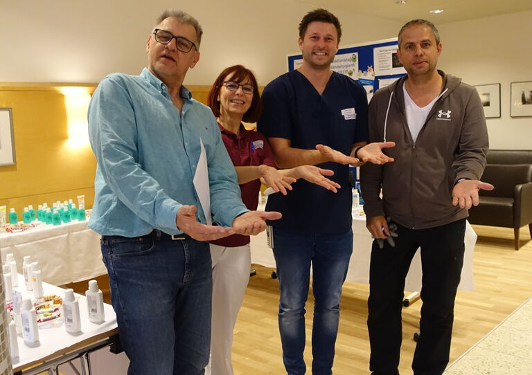 Kolleg*innen aus der Tokiostraße stehen zusammen und halten die Hände in die Kamera