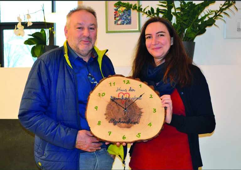 Edi Pross übergibt Heimleiterin Barbara Gerhart eine geschnitzte Holzarbeit.