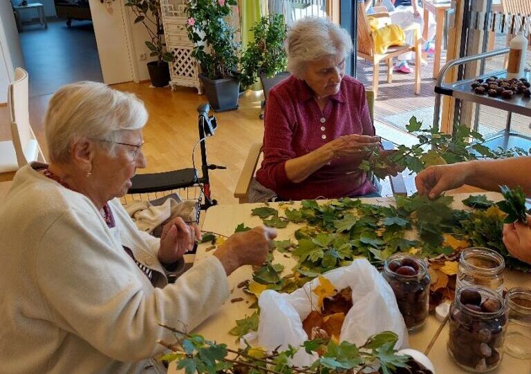Zwei Bewohnerinnen basteln mit Laub