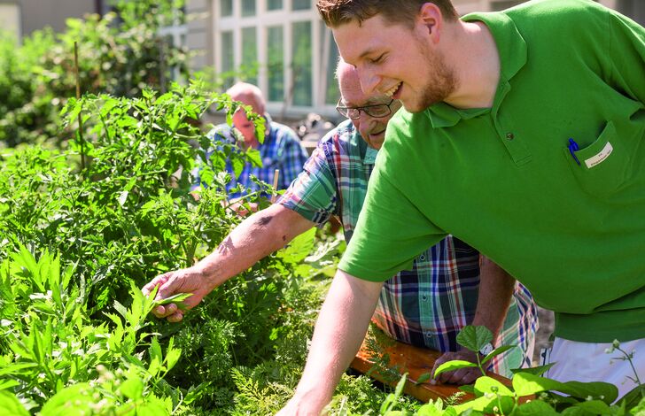 Mitarbeiter und Bewohner bei der Gartentherapie.