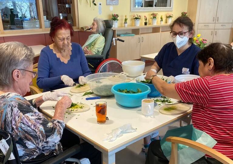 Bewohnerinnen und eine Mitarbeiterin bereiten Pesto zu.