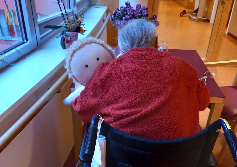Bewohnerin Elsa von hinten mit der Schutzengelpuppe im Arm.