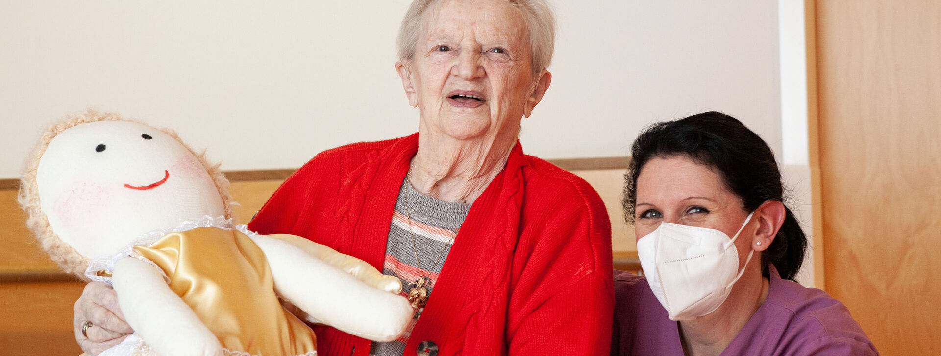 Bewohnerin Elsa hält einen Schutzengel und Bewohnerin Daniela kniet daneben. 