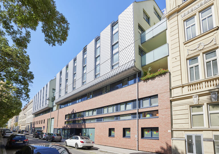 Außenansicht der HABIT WG Schanzstraße, modernes Wohnhaus in einer Straße mit Bäumen 