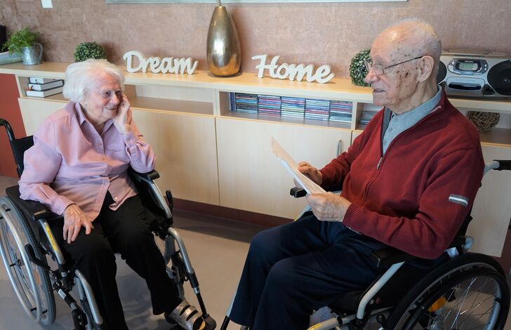 Ein Bewohner liest einer Bewohnerin etwas vor