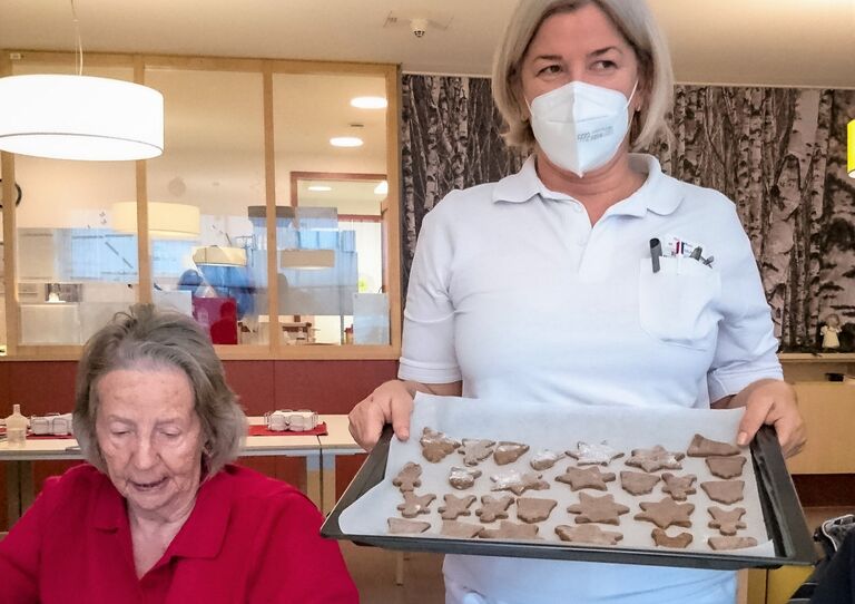 Eine Mitarbeiterin präsentiert ein Blech mit fertigen Keksen.