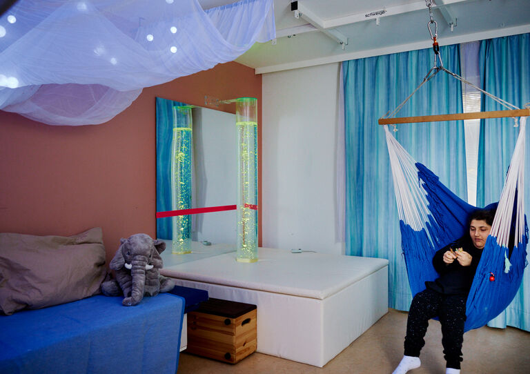 BTZ Maria-Rekker-Gasse Snoezelen-Raum: eine Kundin sitzt in der Hängematte.