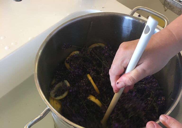 Aufnahme von einem Topf mit Lavendel, der gerade gekocht und umgerührt wird. 