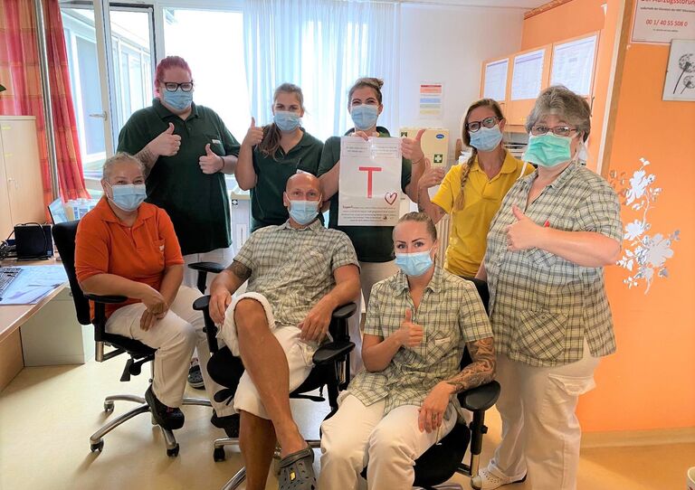 Einige Mitarbeiter aus dem Clementinum stehen für ein Gruppenbild zusammen und halten den Buchstaben "T" hoch, den sie bei der Teamchallenge gefunden haben.