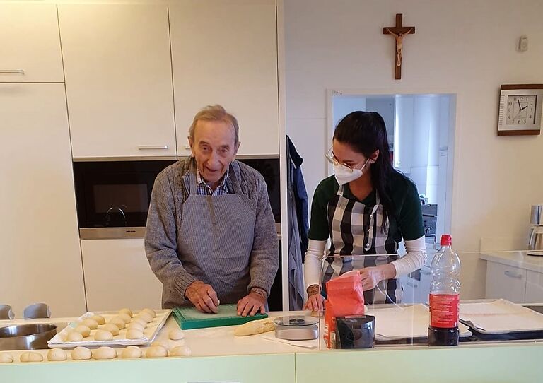 Ein Bewohner und eine Mitarbeiterin formen Krapfen aus dem Teig.