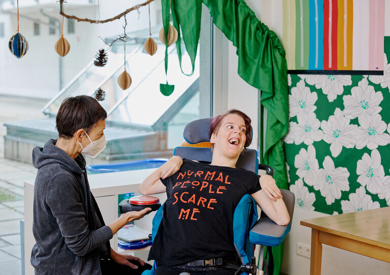 BTZ Lobenhauerngasse: Eine Mitarbeiterin lacht mit einer Kundin, die im Rollstuhl sitzt. 