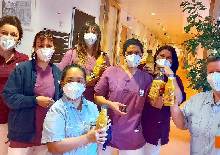 Mitarbeiter*innen stehen für ein Gruppenbild zusammen und halten jeweils eine Flasche Innocent Smoothie hoch.