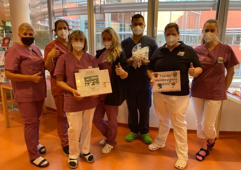 Sieben Mitarbeiter*innen zeigen ihre Geschenke in die Kamera.