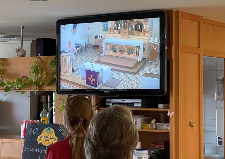 Mitarbeiterinnen verfolgen TV-Übertragung.