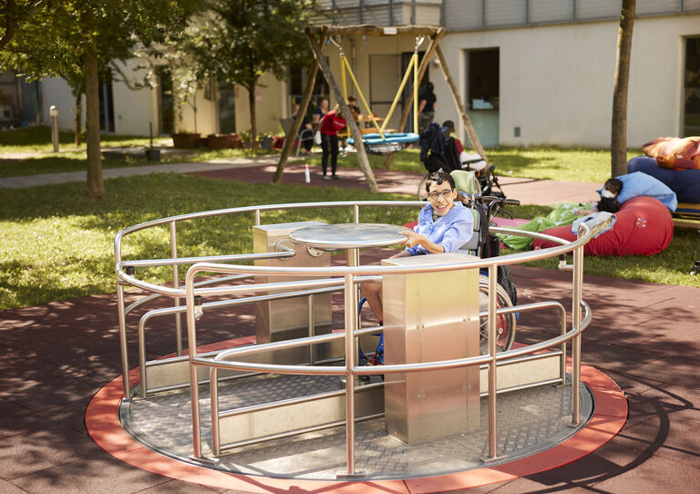 Kunde sitzt am Spielplatz am Ringelspiel