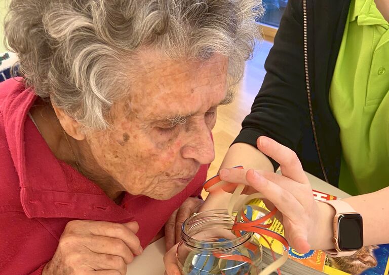 Bewohnerin pustet einen Luftschlange in ein Glas.