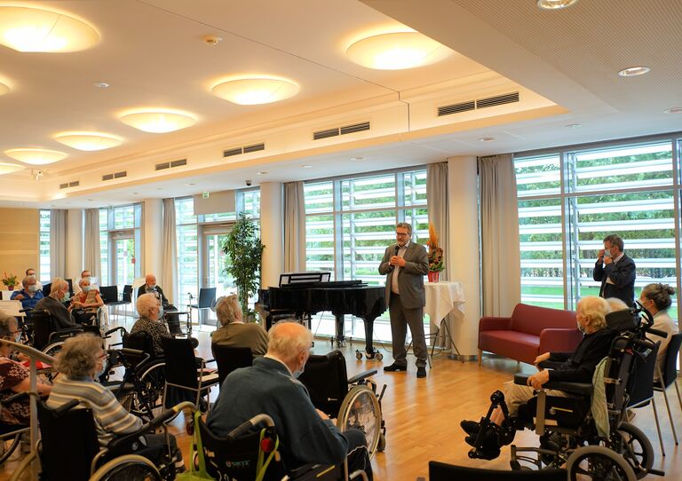 Stadtrat Peter Hacker spricht zu den Bewohnerinnen und Bewohnern im Festsaal.