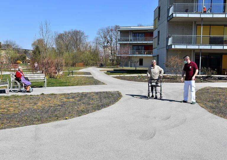 Bewohnerin und Pfleger genießen die Sonne im Hof
