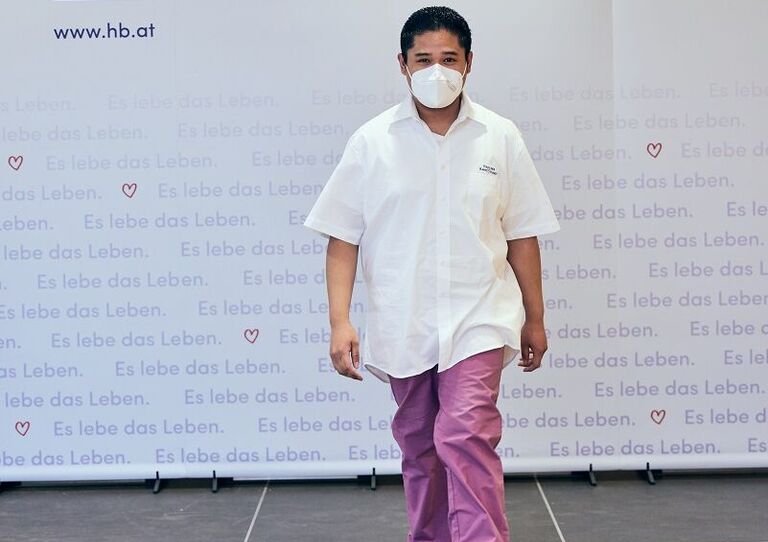 Ein Mitarbeiter mit einer brombeerfarbenen Hose auf dem Laufsteg.