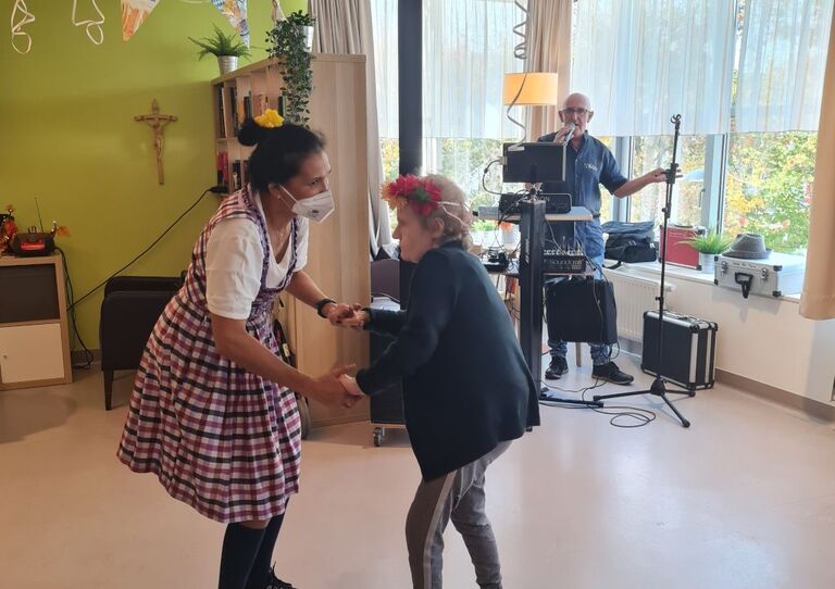 Eine Bewohnerin und eine Mitarbeiterin tanzen miteinander.