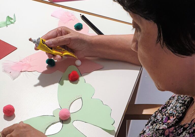 Eine Bewohnerin dekoriert eine Faschingsmaske.