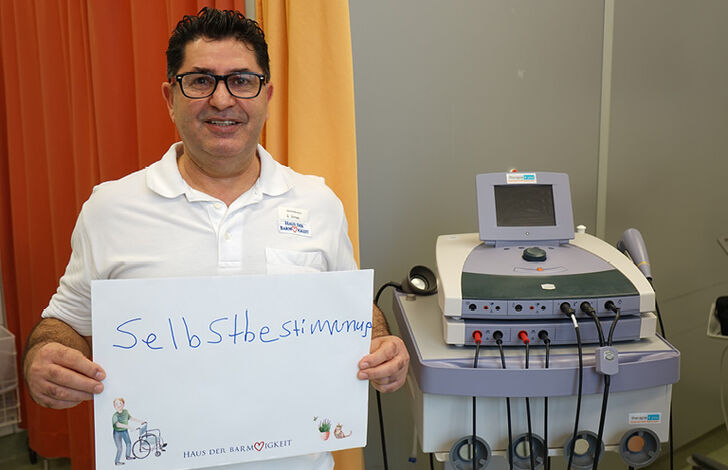 Mitarbeiter hält Schild mit Selbstbstimmung.