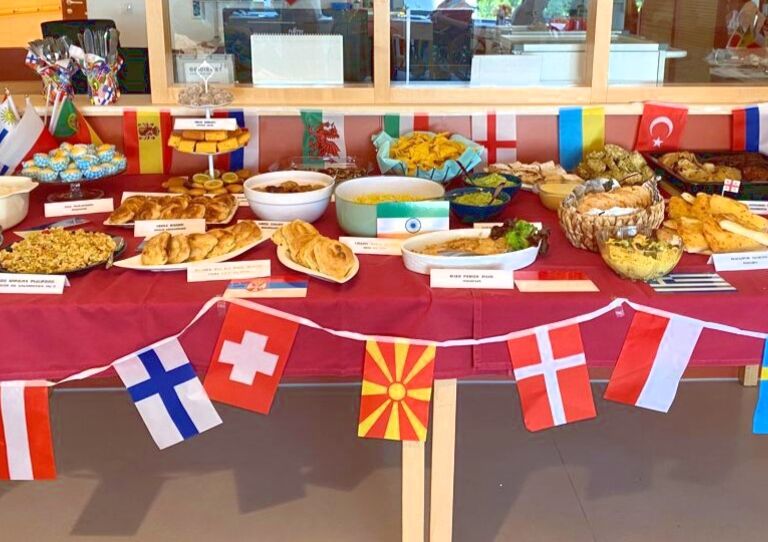 Ein Foto vom Buffet mit lauter Speisen aus der internationalen Küche. Außerdem kleine Fähnchen und andere Dekoration.
