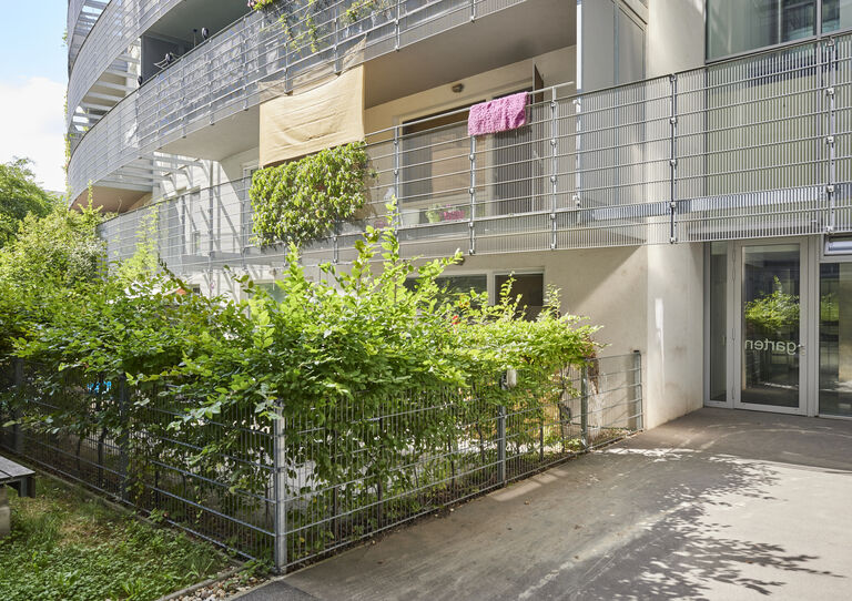 Gartenansicht der HABIT WG Attemsgasse mit Büschen hinter einem Zaun