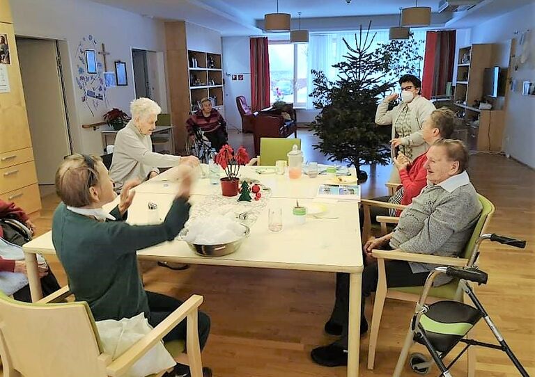 Bwohnerinnen sitzen an einem Tisch und formen Schneekugeln.