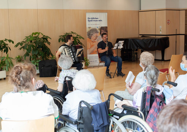 Bewohner*innen und Mitarbeiter*innen lauschen dem Konzert.