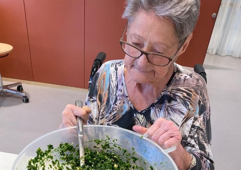 Eine Bewohnerin blickt in eine Schüssel Bärlauch
