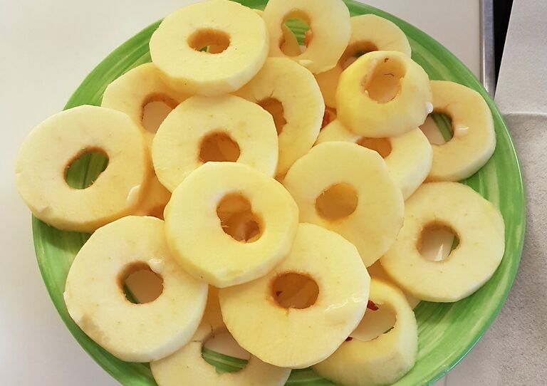 Ein Teller mit geschälten, in Scheiben geschnittenen Äpfeln.