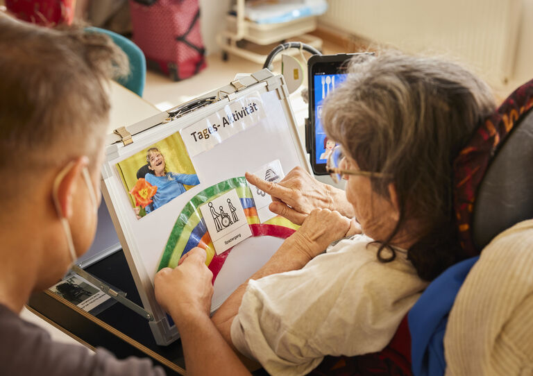 Kundin von hinten, zeigt auf eine Zeichnung und ein Mitarbeiter sitzt neben ihr