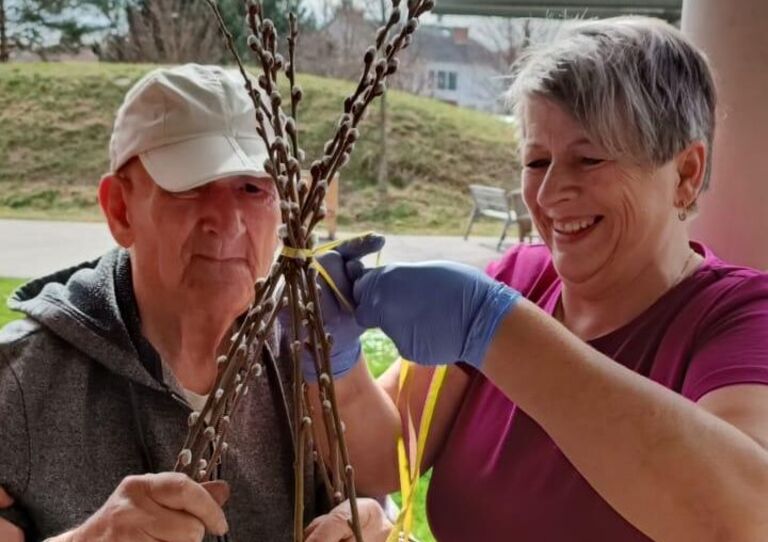 Mitarbeiterin und Bewohner binden einen Palmstrauch