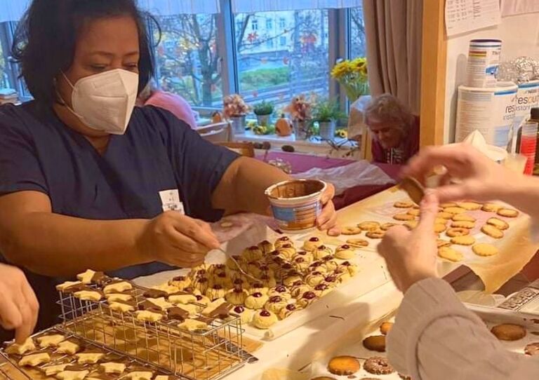 Eine Mitarbeiterin befüllt Kekse mit Marmelade.