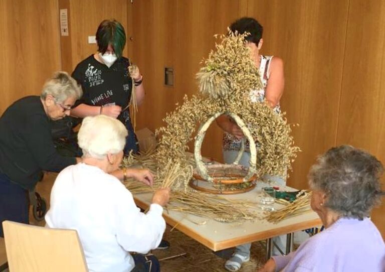 Vier Bewohner*innen, die an der Erntedankkrone basteln.