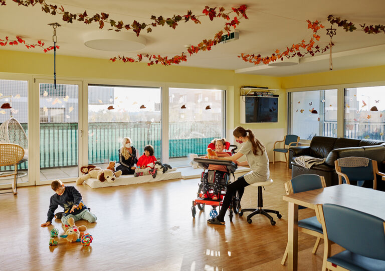 Eine Aufnahme vom Wohnzimmer, in dem sich einige Kund*innen und eine Mitarbeiterin befinden.