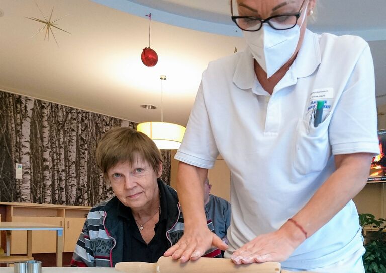 Eine Bewohnerin und eine Mitarbeiterin beim Teig ausrollen.