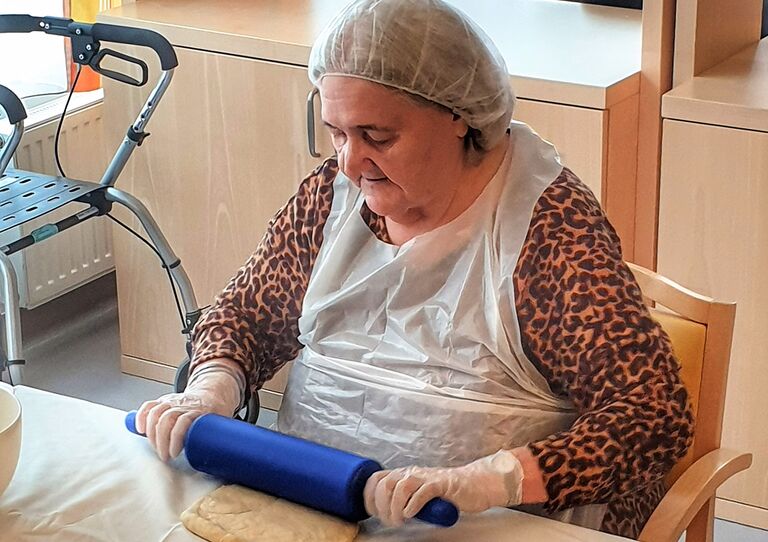 Eine Bewohnerin rollt den Teig aus.