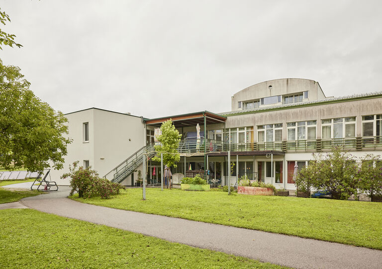 Gartenansicht der HABIT WGs Clementinum mit Rasenfläche, Weg, Büschen