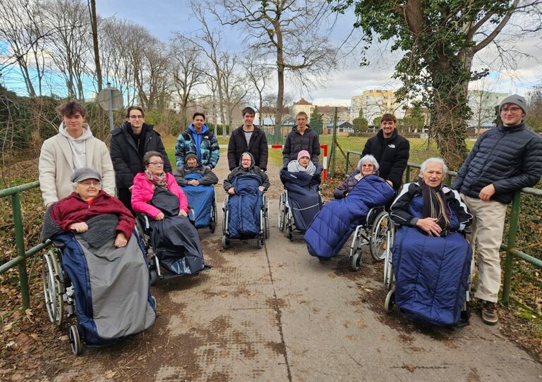 Zivildiener schieben Bewohner*innen im Rollstuhl 7 Zivildiener im Kreis aufgestellt mit sieben Bewohner*innen im Rollstuhl