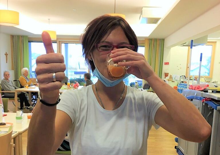 Eine Mitarbeiterin probiert den Saft und streckt den Daumen nach oben.